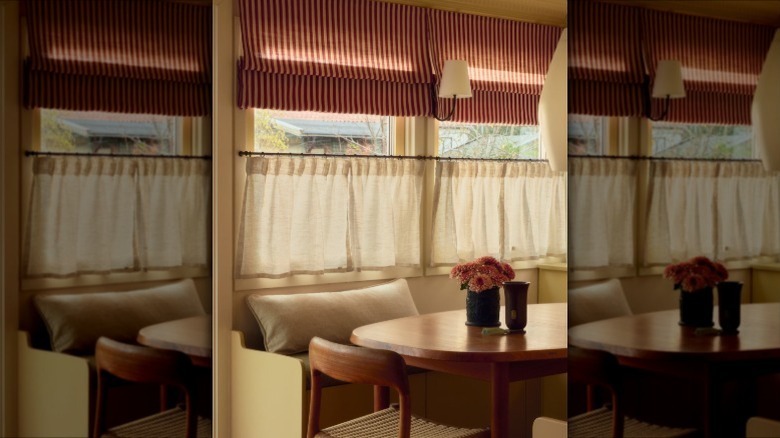 Kitchen windows with red and white striped Roman shades and white cafe curtains