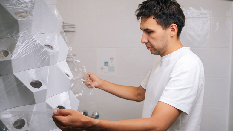 A man unwraps a new hydroponics tower inside his home.
