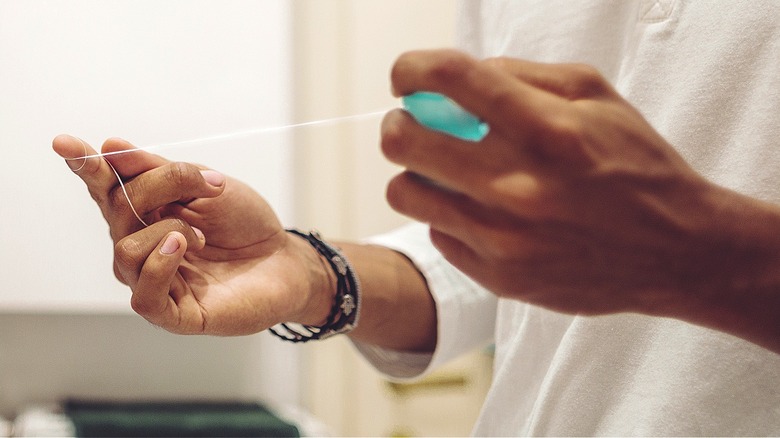 Person pulling out dental floss