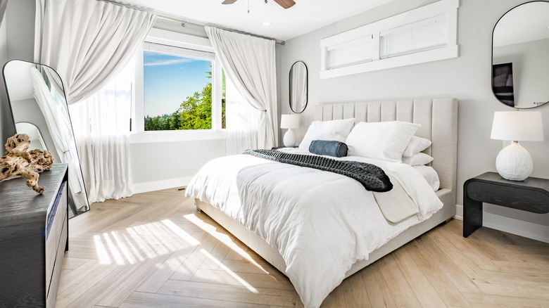 A light colored bedroom with the windows open.