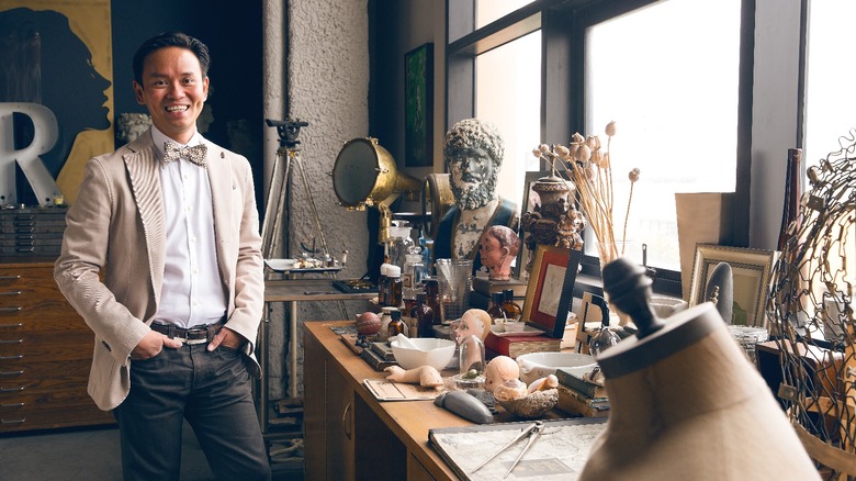 Jonathan Rachman smiling with cluttered table