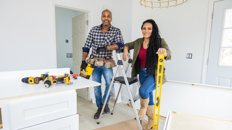 Egypt Sherrod and Mike Jackson posing with tools during renovation