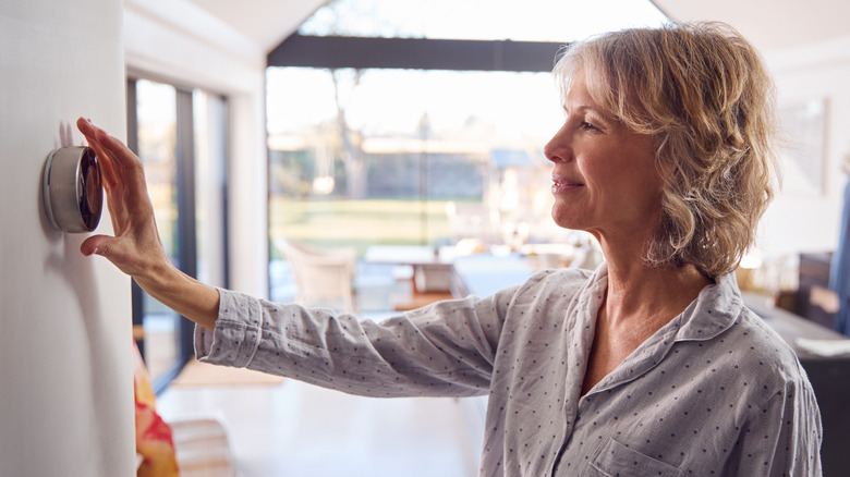 woman adjusting thermostat