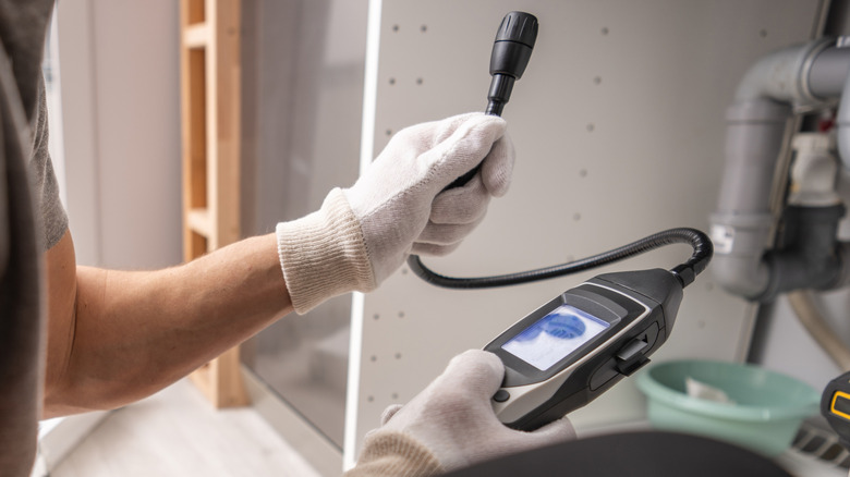 A man holding a gas leak detector
