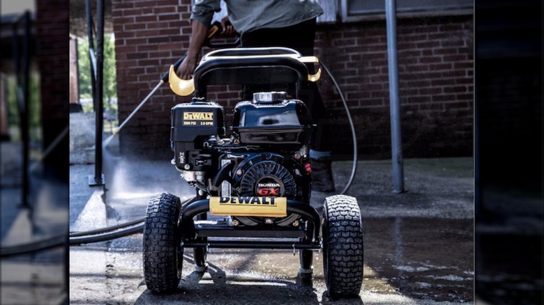 A man uses a DeWalt 3200 PSI Gas Powered Pressure Washer to clean a driveway