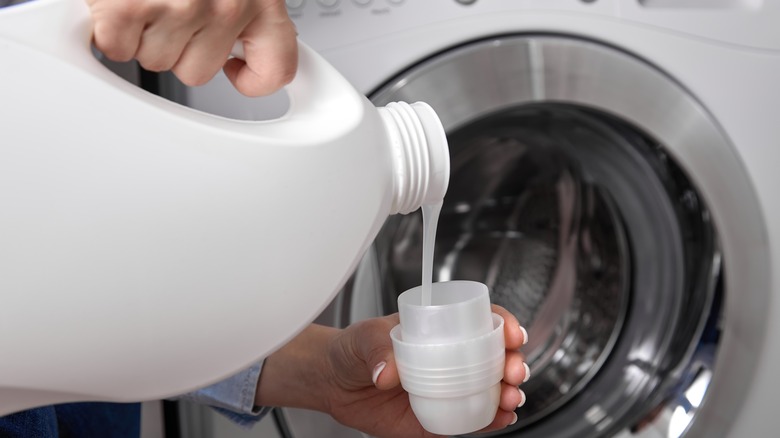 hands pouring liquid laundry detergent