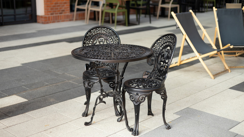 Black iron table and chairs with intricate detailing on a patio
