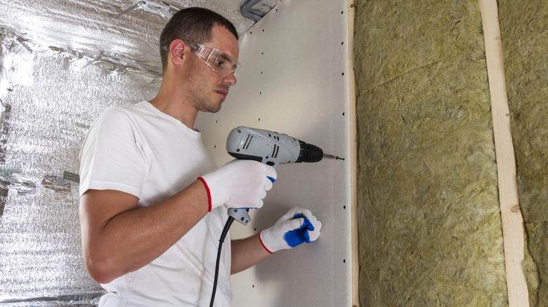 Man hanging a sheet of drywall