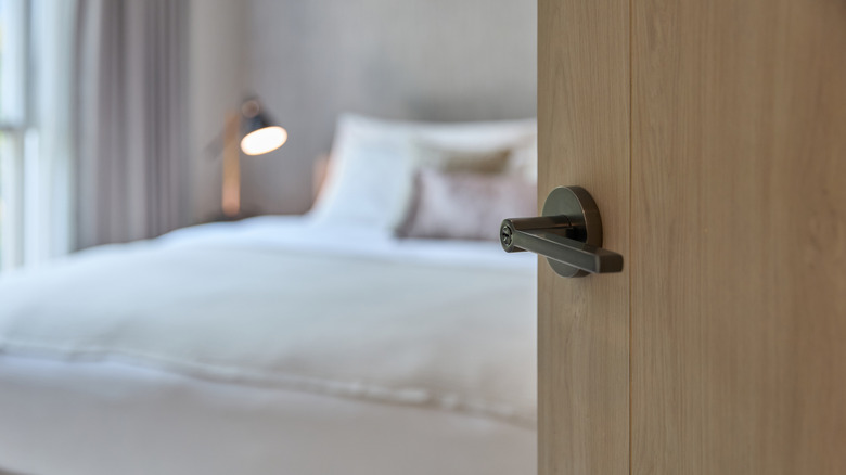 A close up of a door handle leading into a bedroom.