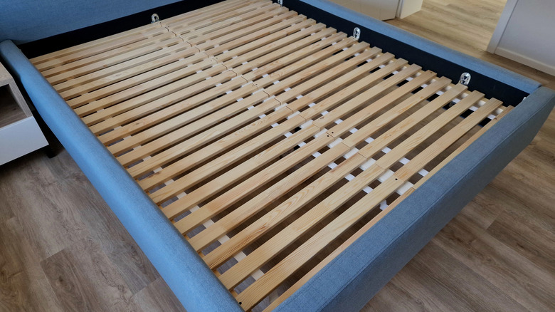 a blue fabric bed frame with wooden slats exposed
