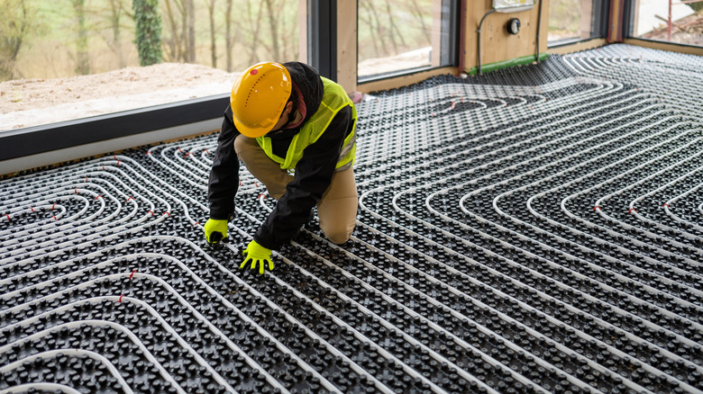 A man installs a hydronic radiant heat system