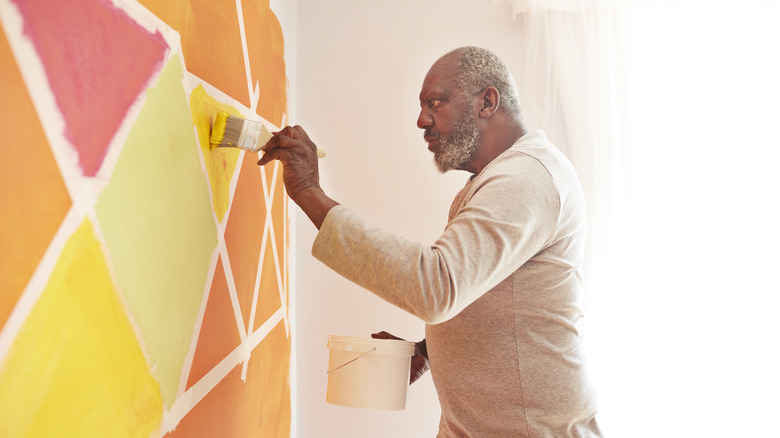 Man painting a wall with geometric patterns