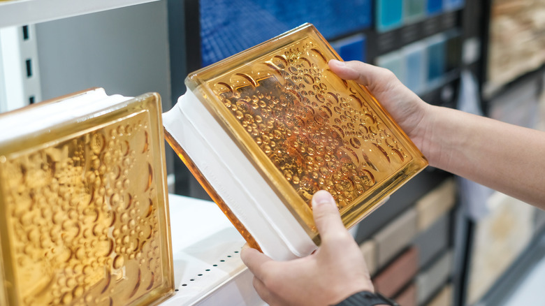 Man examining glass blocks in store.