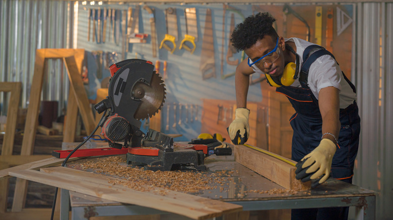 A man measuring a piece of wood in a workshop