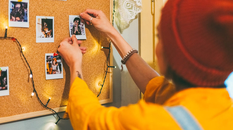 Woman pinning photographs to a cork board