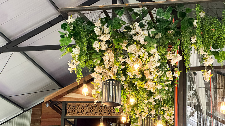 Faux flowers hung from chicken wire mounted to the ceiling in large open-plan home.