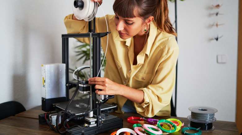 A woman loads filament into a 3D printer