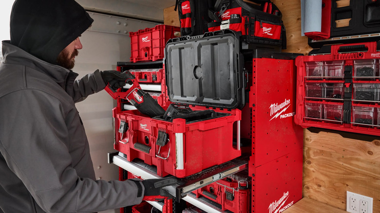 A person putting a tool in a Milwaukee toolbox