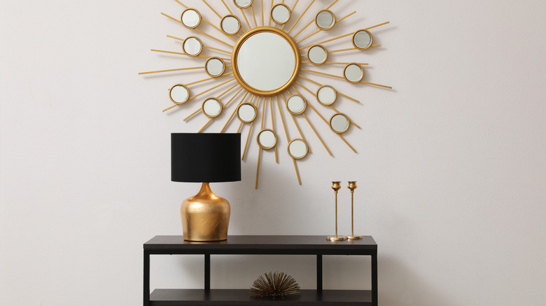 An entryway table with a lamp, candlesticks, and a book on it as decoration