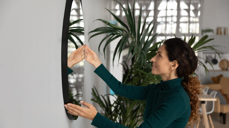 Woman hanging a mirror on the wall