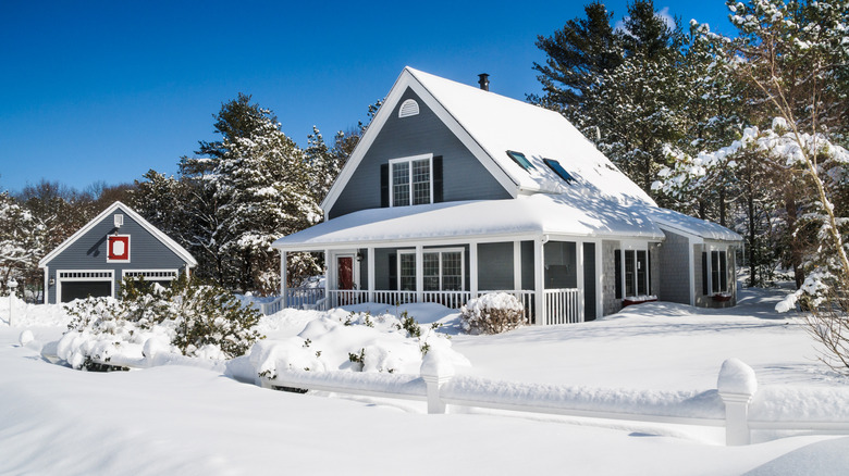 A small home with garage covered in thick layers of snow