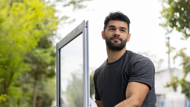 A young man is preparing to install a storm window