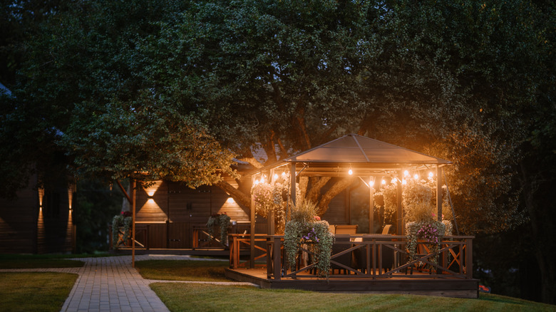 An illuminated backyard, featuring a gazebo.
