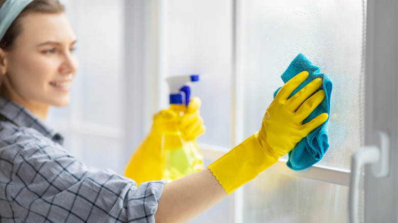 Woman wipes down window to clean