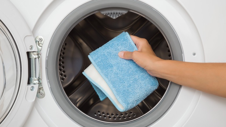 A person puts a reusable mop pad into a washing machine