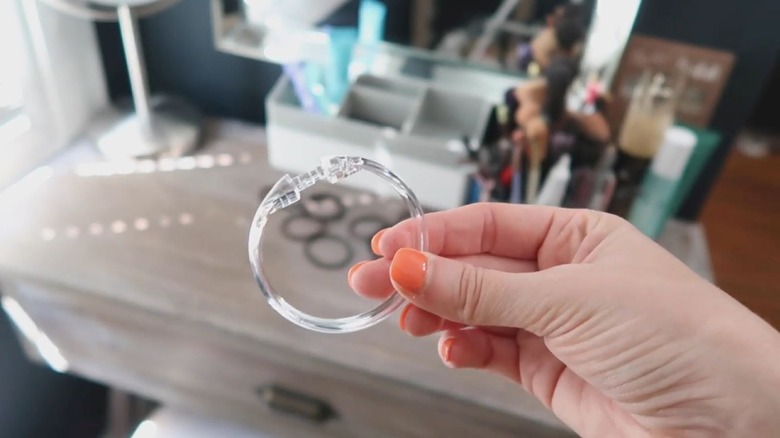 DIY storage container made of shower curtain rings next to two candles