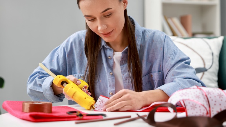 A woman using a hot glue gun for a project.