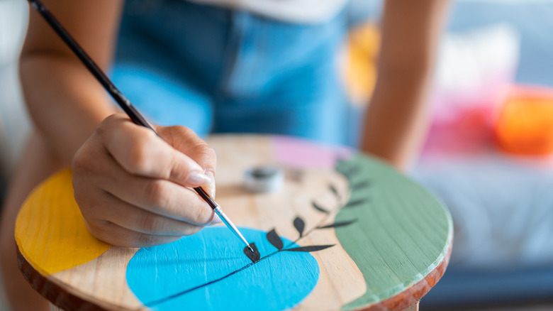 Close up of person painting a wooden circle