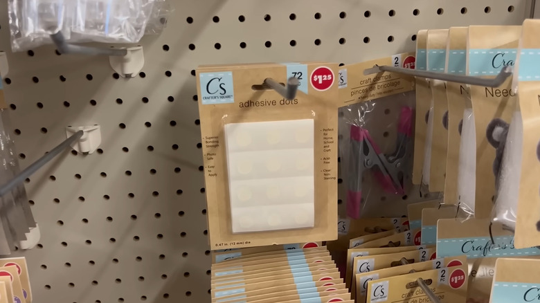 Packages of Dollar Tree adhesive dots hanging in store