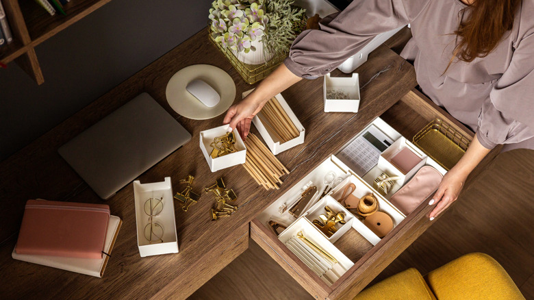 Closeup of person's hands tidying a desk with drawer organizers
