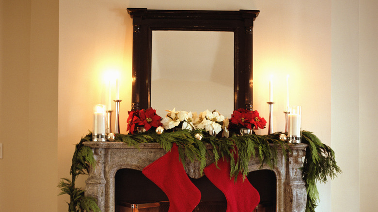 View of a fireplace with poinsettias, candles, and stocking on the mantle