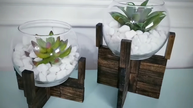 Raised bowls on a wood platform holding white rocks and faux succulents