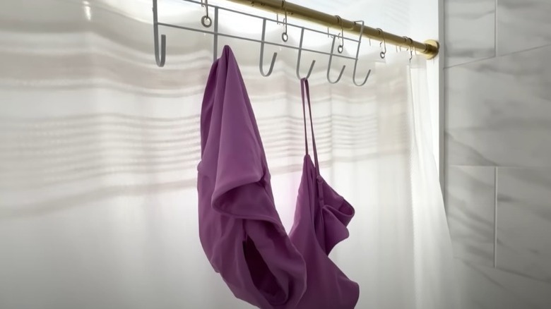 A homeowner demonstrates how to attach a hook hanger to a shower curtain rod.