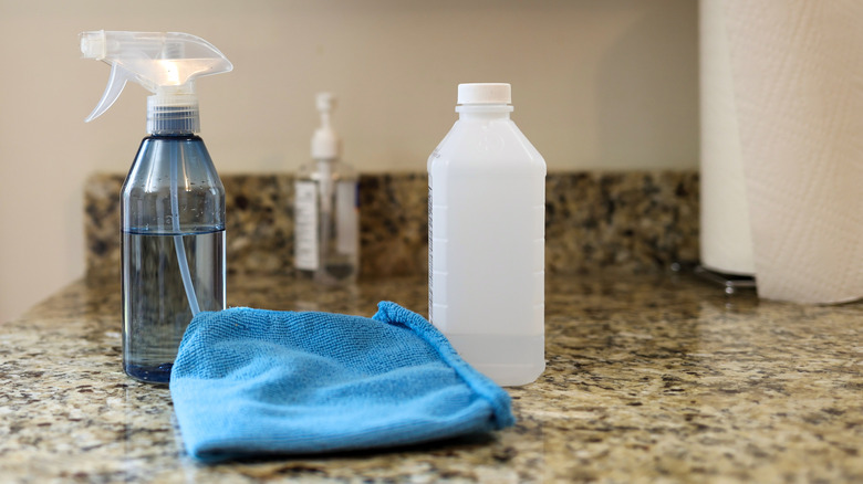 Rubbing alcohol, cloth, and spray bottle on kitchen counter