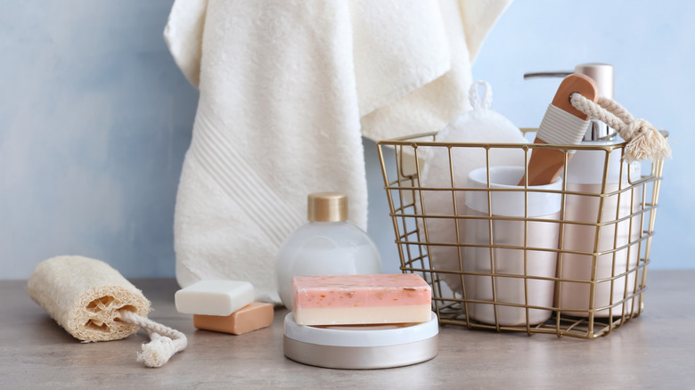 Gold metal wire basket with bath essentials in it and around it on a counter