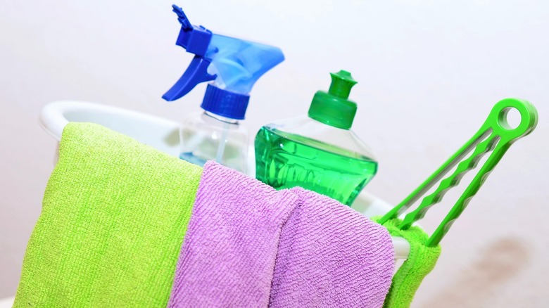 Bucket of cleaning supplies with spray bottle soap and rags