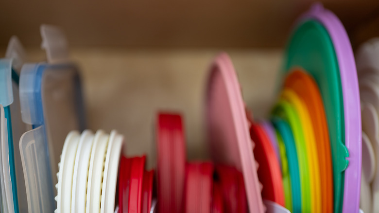 Various container lids are lined up in a cupboard