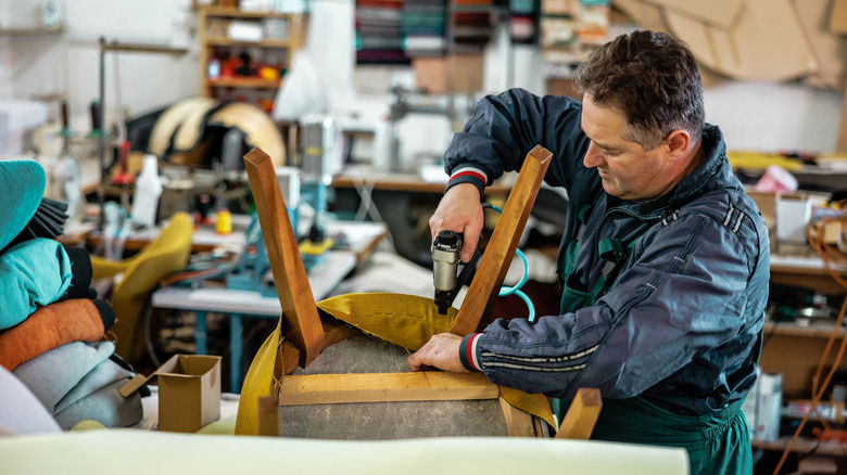 A restoration expert stapling fabric to an upholstered chair