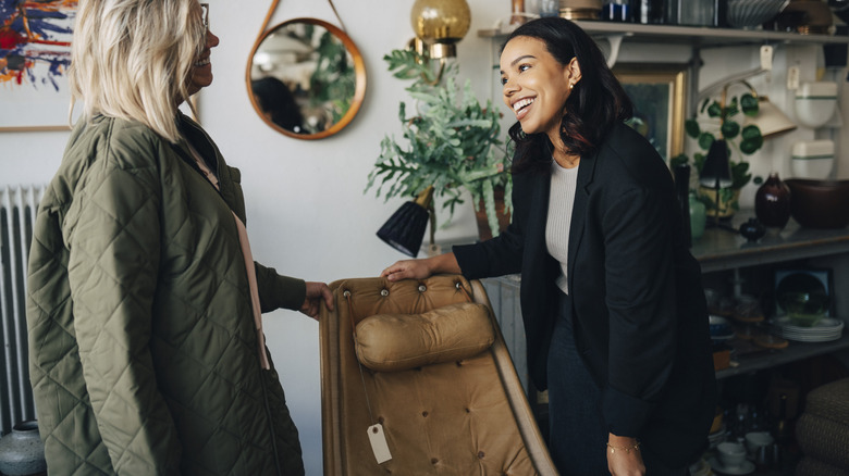 Two people discussing a leather upholstered chair in a store