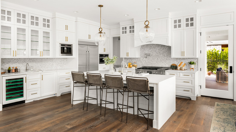 A modern kitchen with ceiling high white cabinets, and an island bench with stools