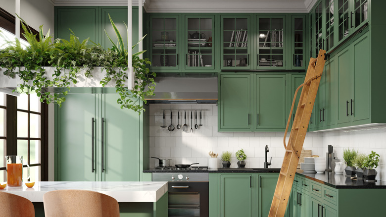 A kitchen with green ceiling high cabinets and a ladder to help reach the high ones