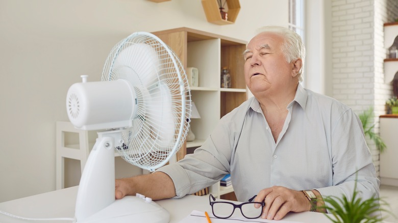 Man sitting in front of a fan to cool off
