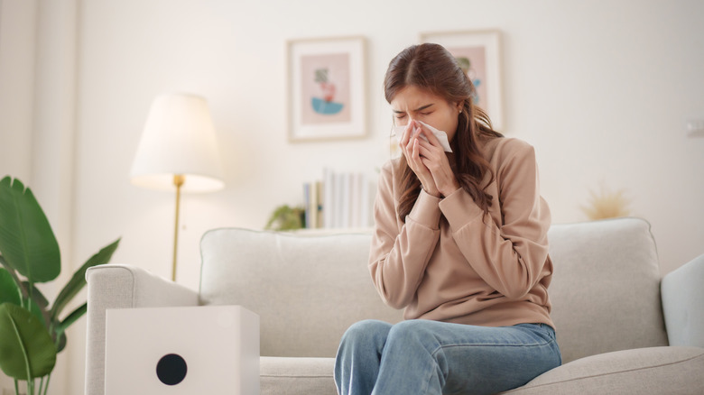Woman sneezing while sitting on a couch