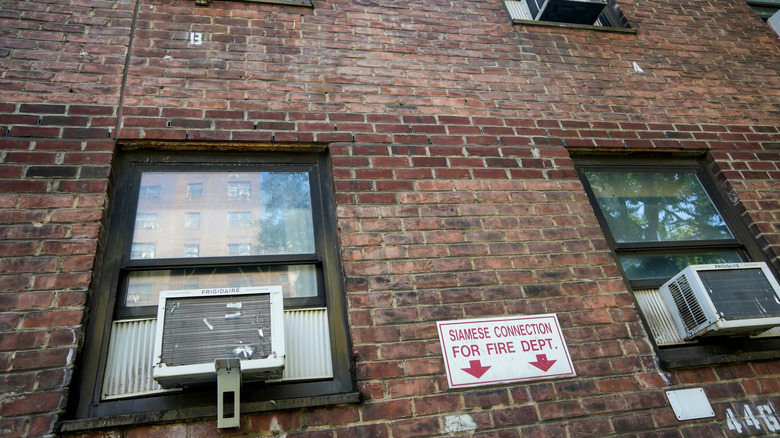 An apartment building with multiple window air conditioners installed in the units