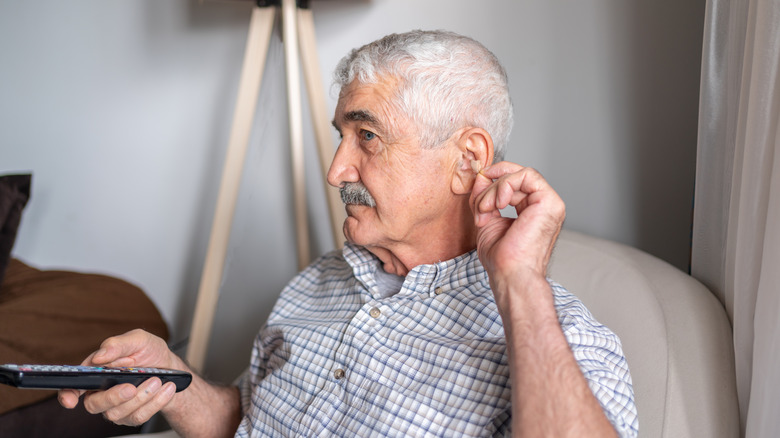 Man turning up the volume on the TV with the remote