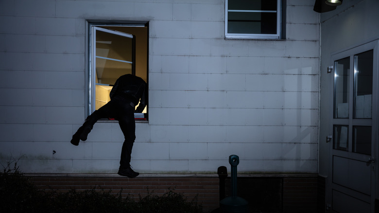 Burglar entering a home through a window